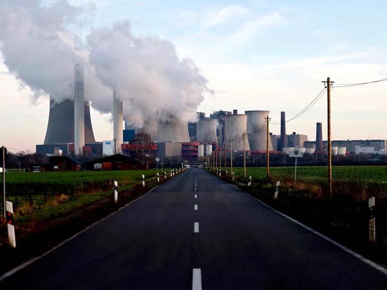 Strommasten um das Kohlekraftwerk Niederaußem des Stromkonzerns RWE. Aus dem Kraftwerk strömt eine dicke graue Wolke. (Symbolbild)