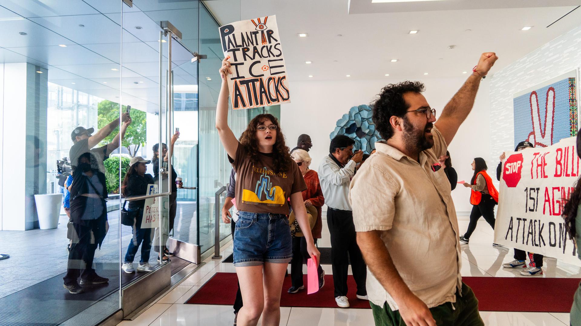 Demonstranten marschieren am 13. Juni 2025 in Los Angeles, USA, mit Plakaten mit der Aufschrift „Palantir Tracks ICE Attacks“ in der Lobby eines Gebäudes. Demonstranten marschieren am 13. Juni 2025 in Los Angeles, USA, mit Plakaten mit der Aufschrift „Palantir Tracks ICE Attacks“ in der Lobby eines Gebäudes.