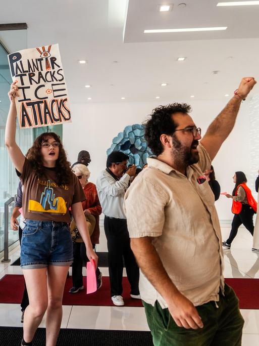 Demonstranten marschieren am 13. Juni 2025 in Los Angeles, USA, mit Plakaten mit der Aufschrift „Palantir Tracks ICE Attacks“ in der Lobby eines Gebäudes. Demonstranten marschieren am 13. Juni 2025 in Los Angeles, USA, mit Plakaten mit der Aufschrift „Palantir Tracks ICE Attacks“ in der Lobby eines Gebäudes.