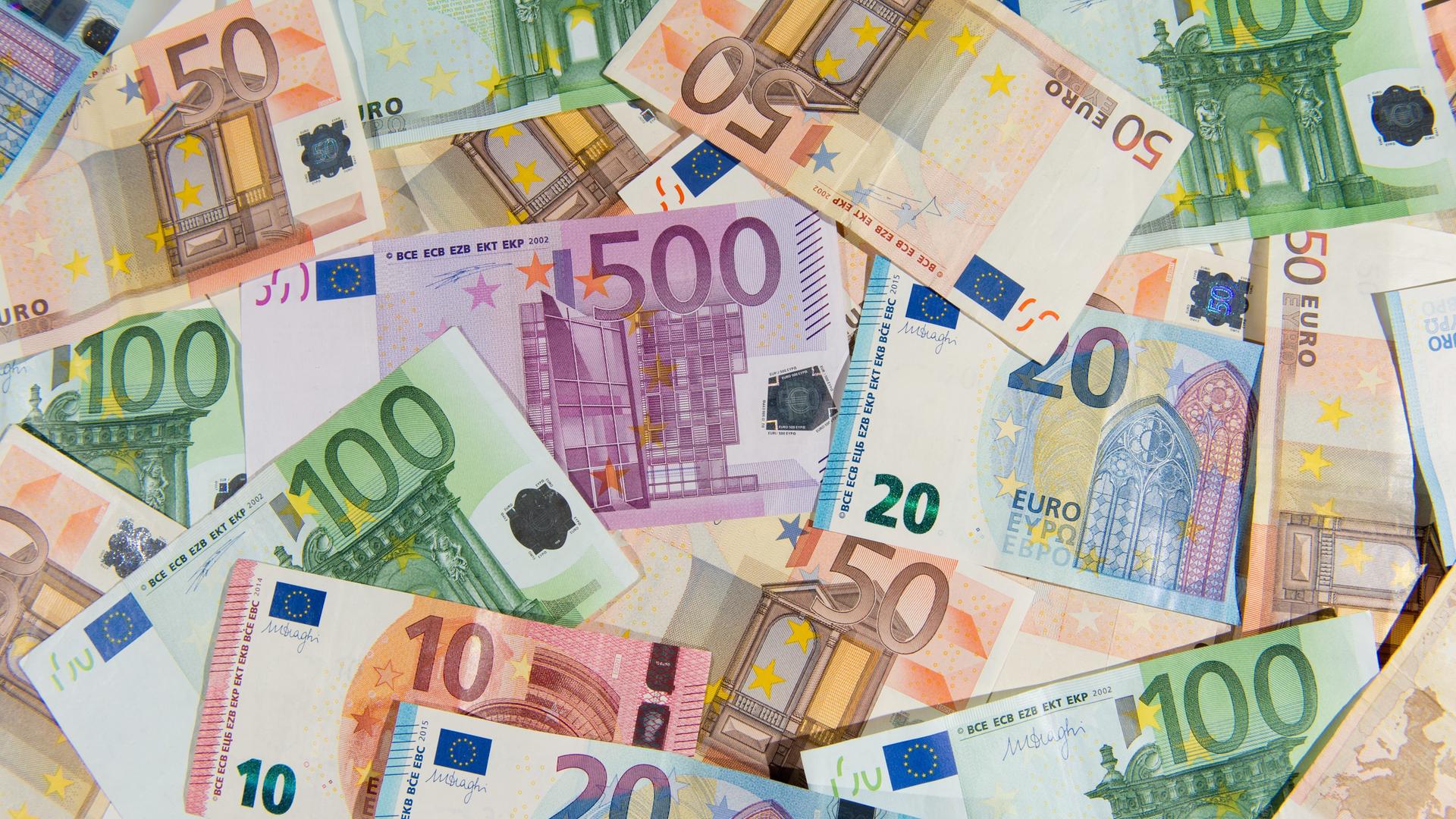 Zahlreiche verschiedene Euro-Geldscheine liegenauf einem Tisch. 