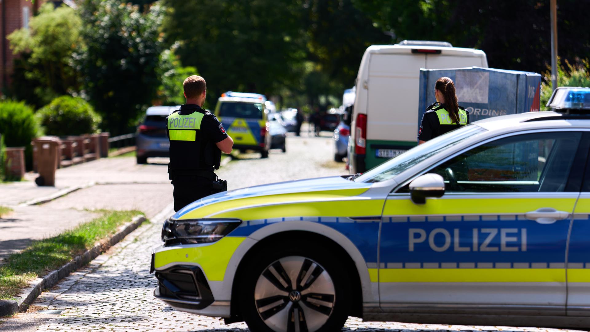 Polizisten stehen auf einer Straße vor dem Haus von der  Jugend-Hilfe in Stade. 