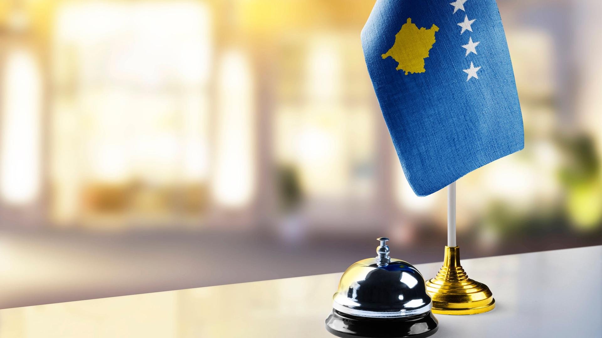 Die Flagge des Kosovo steht auf einem Hoteltresen neben einer Klingel 