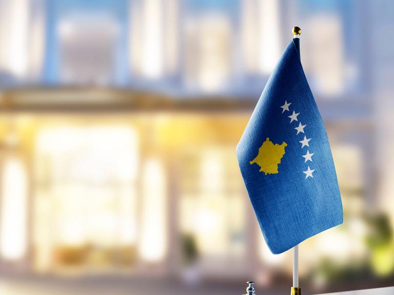 Die Flagge des Kosovo steht auf einem Hoteltresen neben einer Klingel 