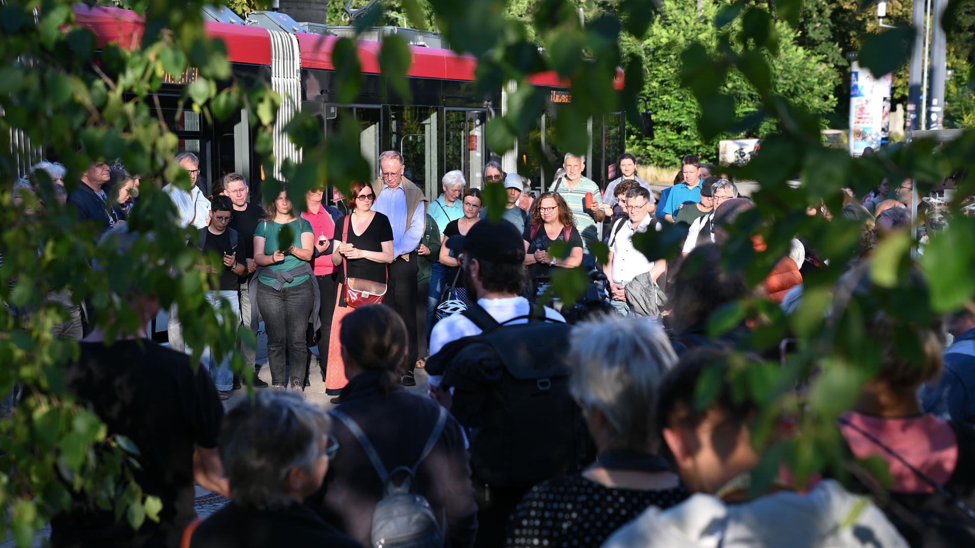 Man sieht durch Bäume hindurch Menschen, die sich an der Lichterkette gegen die AfD beteiligen. 