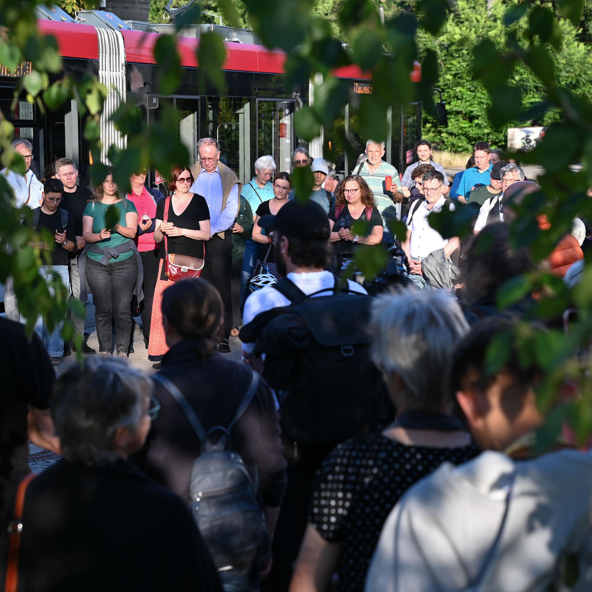 Man sieht durch Bäume hindurch Menschen, die sich an der Lichterkette gegen die AfD beteiligen. 