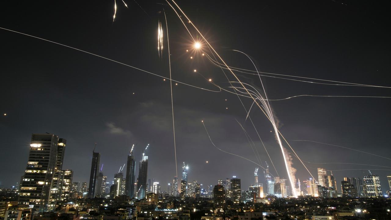 Nachtpanorama mit Skyline von Tel Aviv. Über den Hochhäusen sind iranische Raketen und Gegenraketen der israelischen Abwehr zu sehen