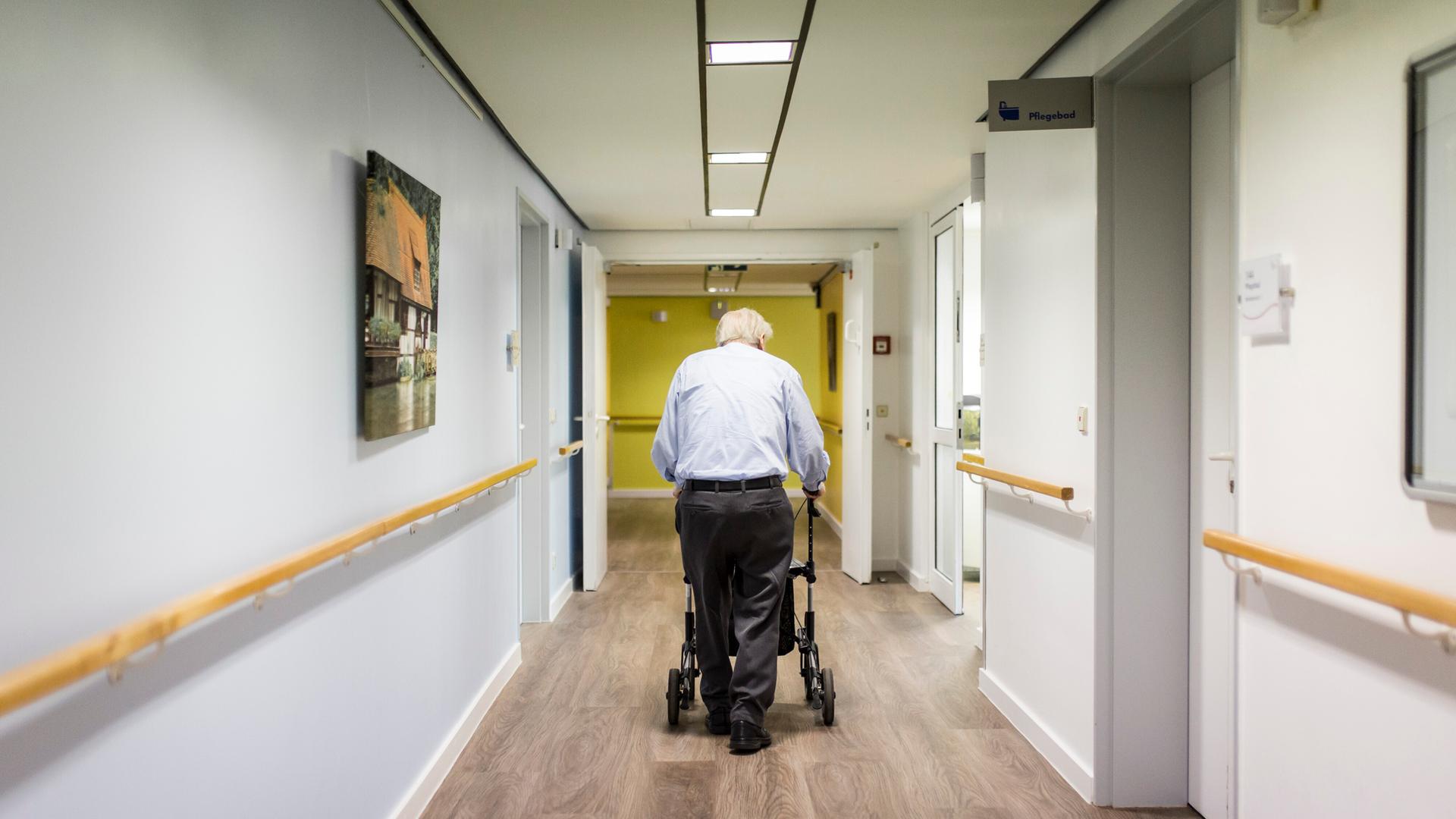 Ein alter Mann läuft mit einem Rollator im Gang einer Pflegeeinrichtung Ein alter Mann läuft mit einem Rollator im Gang einer Pflegeeinrichtung