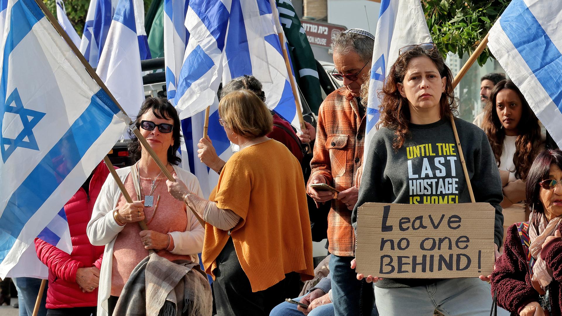 Inmitten einer Menschenmenge mit israelischen Fahnen fordert eine Frau auf einem Schild die Freilassung aller Hamas-Geiseln. 