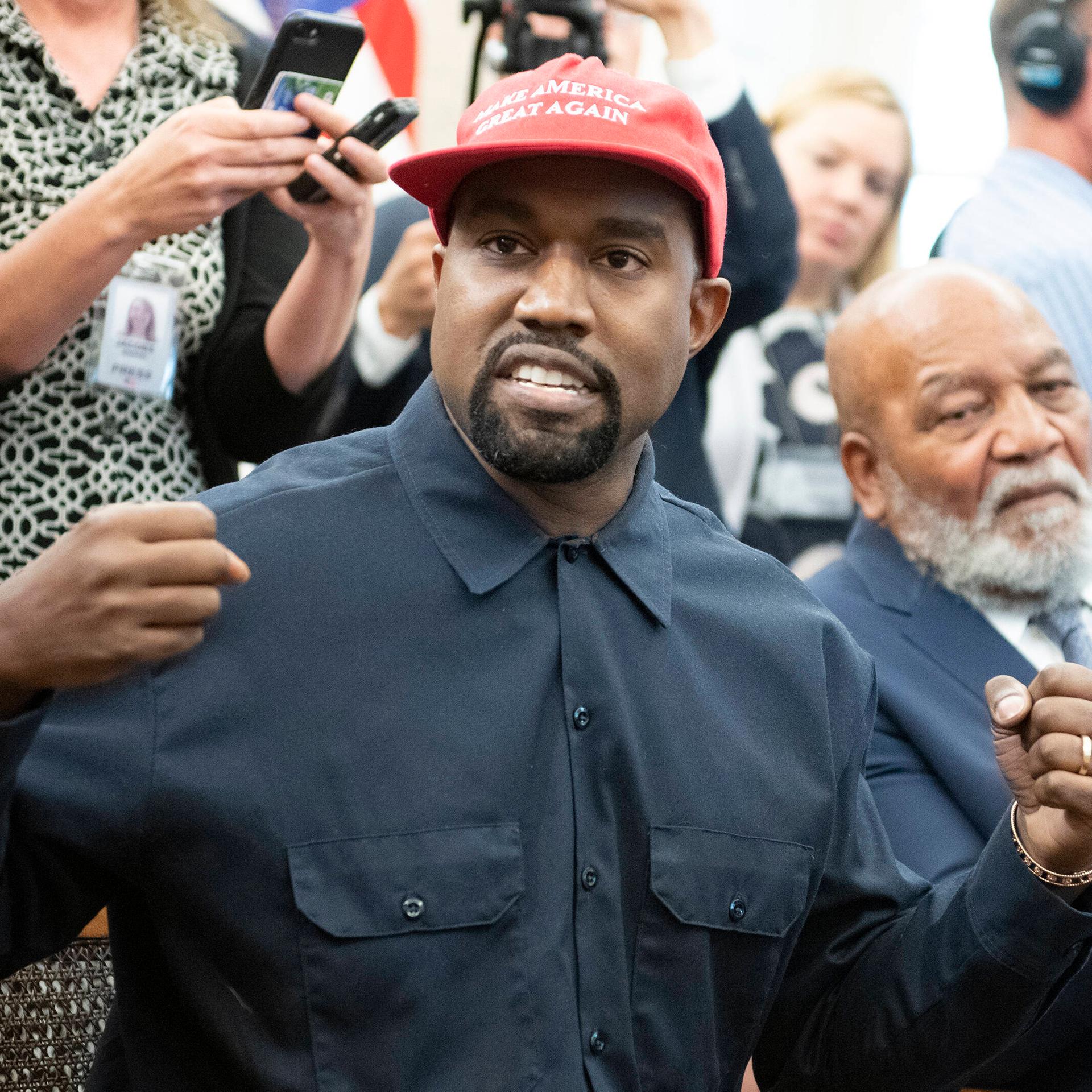 Der US-Rapper Kanye West steht inmitten von Medienvertretern.