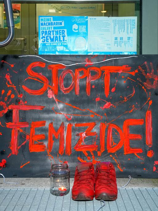 Vor der Eingangstür des Mädchenzentrums Szenenwechsel in Neukölln steht ein Schild mit der Aufschrift "STOPPT FEMIZIDE!". Dazu steht ein paar Schuhe in Orange und ein Teelicht mit brennender Kerze.