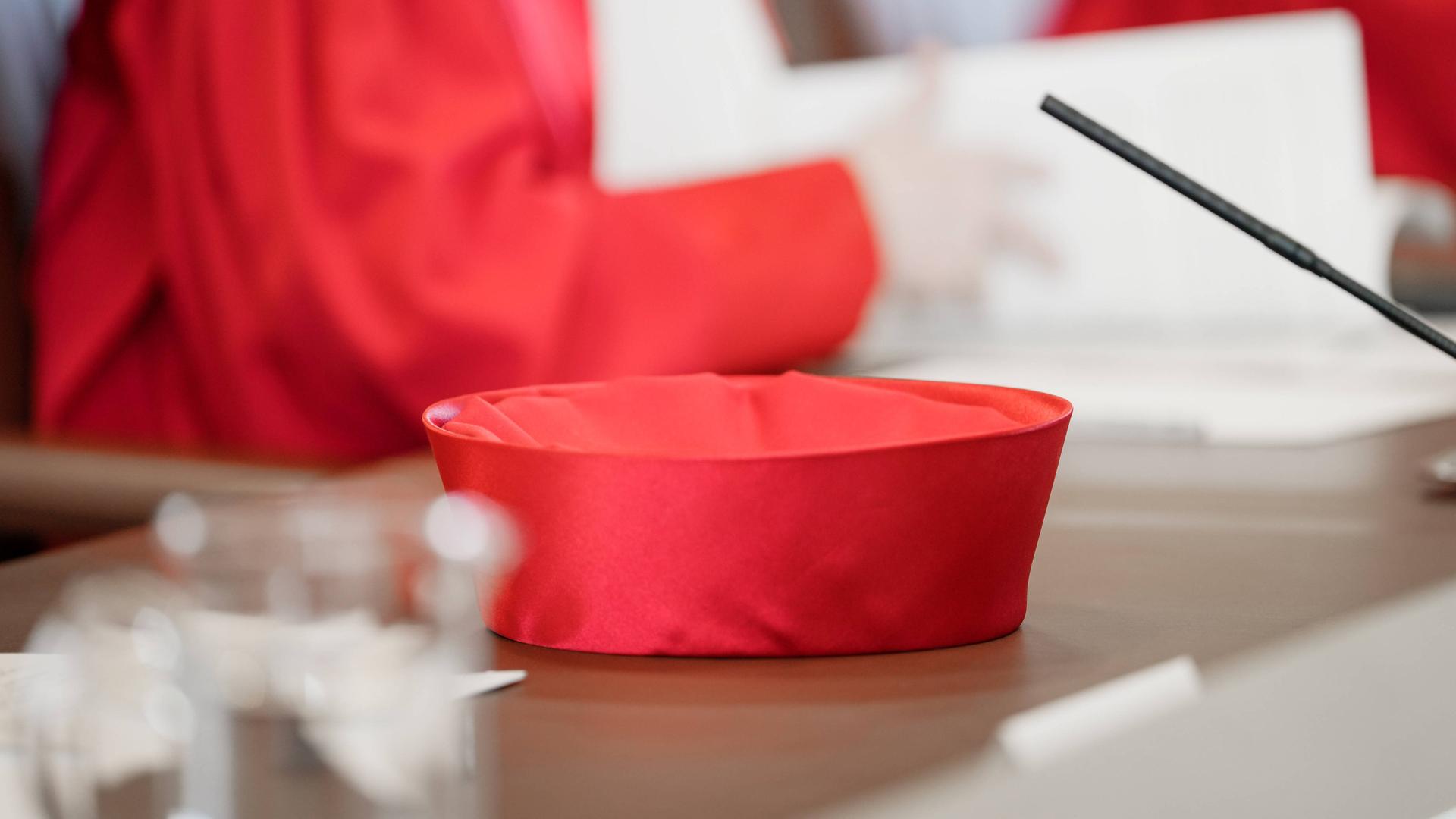 Ein roter Hut der Verfassungsrichter liegt auf einem Tisch.
