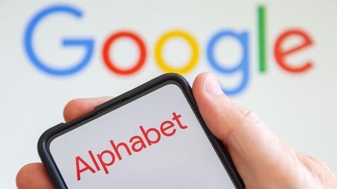 Logo von Alphabet auf einem Smartphone, dahinter das Google-Logo.