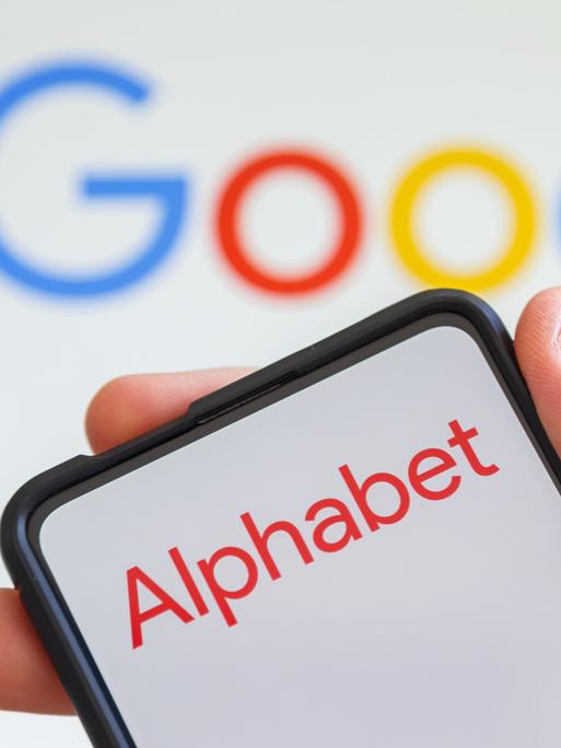 Logo von Alphabet auf einem Smartphone, dahinter das Google-Logo.