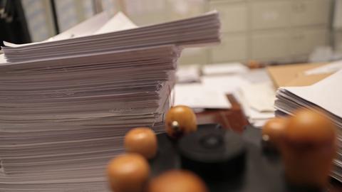 Stempel und Aktenstapel liegen in einem Büro auf dem Schreibtisch. 