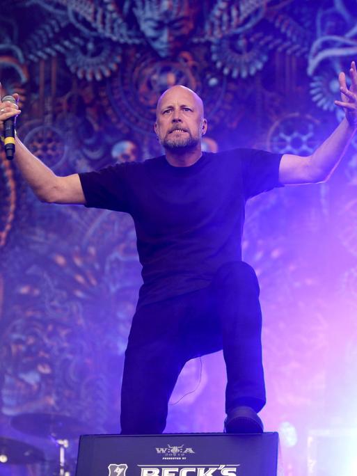 Der Sänger von Meshuggah auf der Bühne. Er fordert mit den armen sein Publikum zum mitsingen auf.