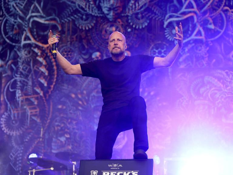 Der Sänger von Meshuggah auf der Bühne. Er fordert mit den armen sein Publikum zum mitsingen auf.