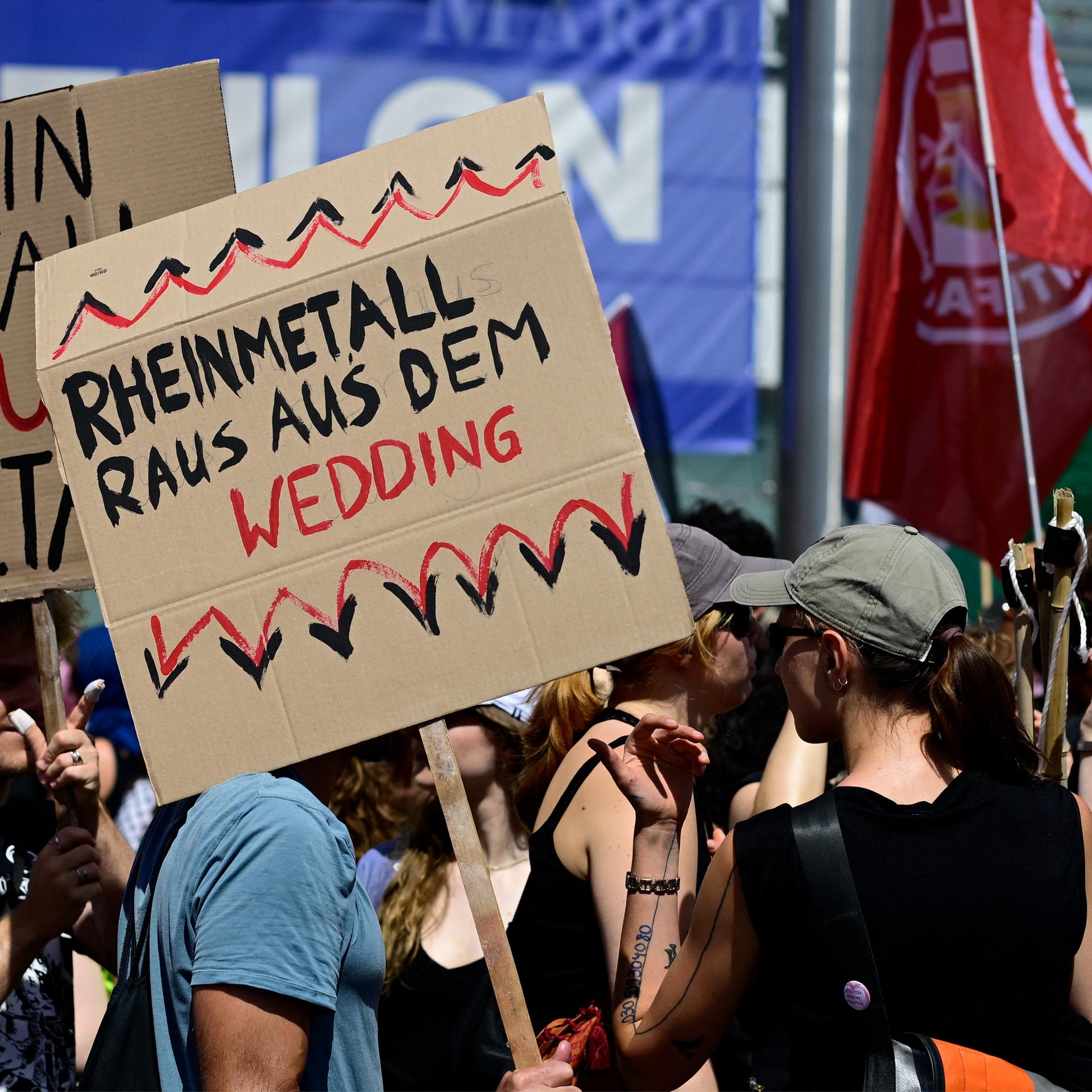 Mehrere Demonstranten stehen nebeneinander. Eine Person hält ein Schild mit der Aufschrift "Rheinmetall raus aus dem Wedding" in die Höhe.