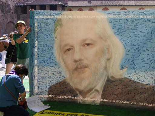 Unterstützer des Whistleblowers Julian Assange mit einem großen Plakat auf dem Wired Next Festival in Mailand am 16. Juni 2024. Das Plakat zeigt den Gründer der Enthüllungsplattform Wikileaks mit grauem Bart und langen Haaren.