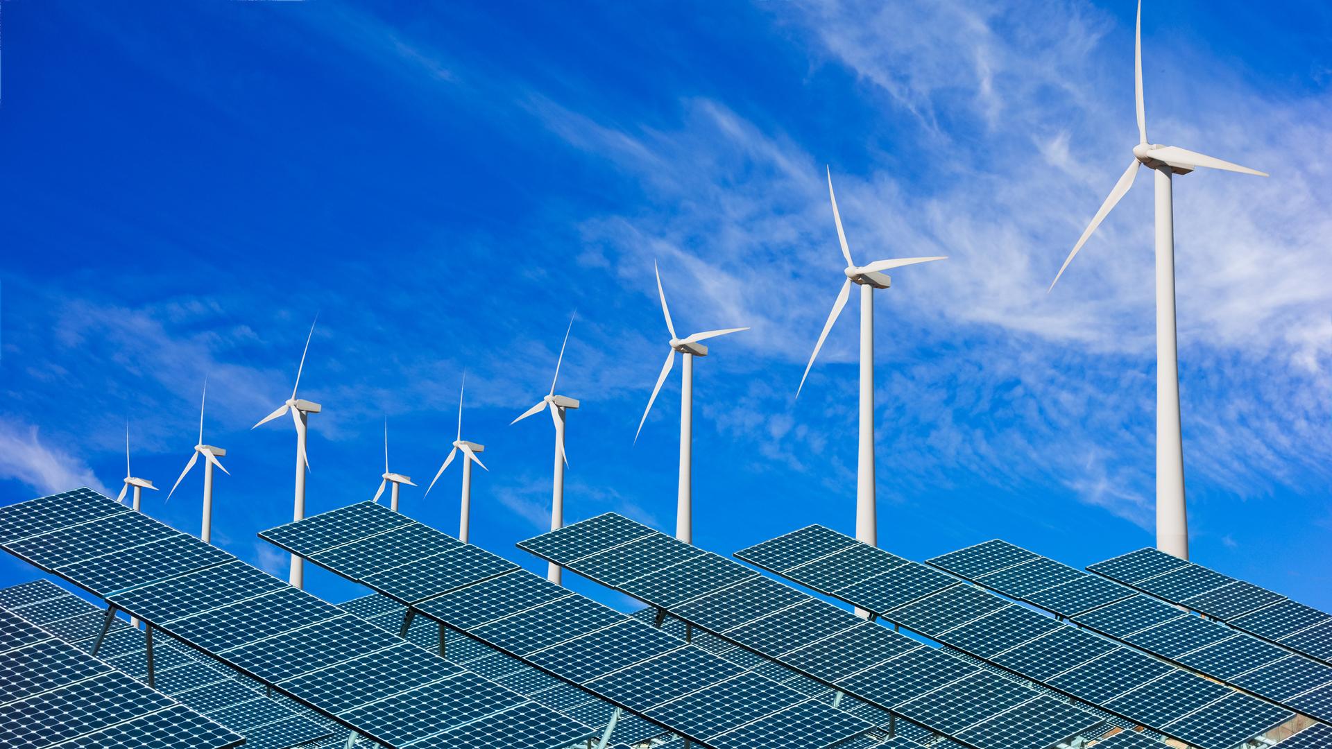 Solarzellen und Windkraftanlagen vor blauem Himmel

