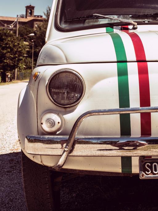 Ein Original Fiat 500 in weiß mit den Farben der italienischen Flagge auf der Kühlerhaube.