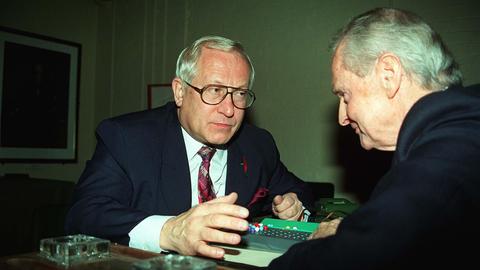Zwei ältere Männer sitzen sich gegenüber und spielen ein Spiel. Sie tragen Anzug. Der linke Mann ist der ehemalige Doppelagent Oleg Gordijewski.