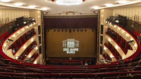 Die Bühne des Wiener Burgtheaters, vom obersten Rang aus gesehen. Zwischen dem roten Vorhang auf der Bühne steht auf einer Leinwand: "250 Jahre Burg" Die Bühne des Wiener Burgtheaters, vom obersten Rang aus gesehen. Zwischen dem roten Vorhang auf der Bühne steht auf einer Leinwand: "250 Jahre Burg"