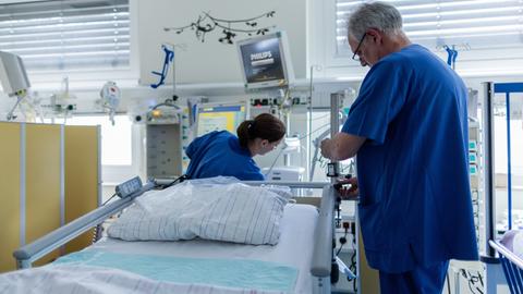 In einem Krankenhaus richten eine Pflegerin und Pfleger ein Intensivbett her.