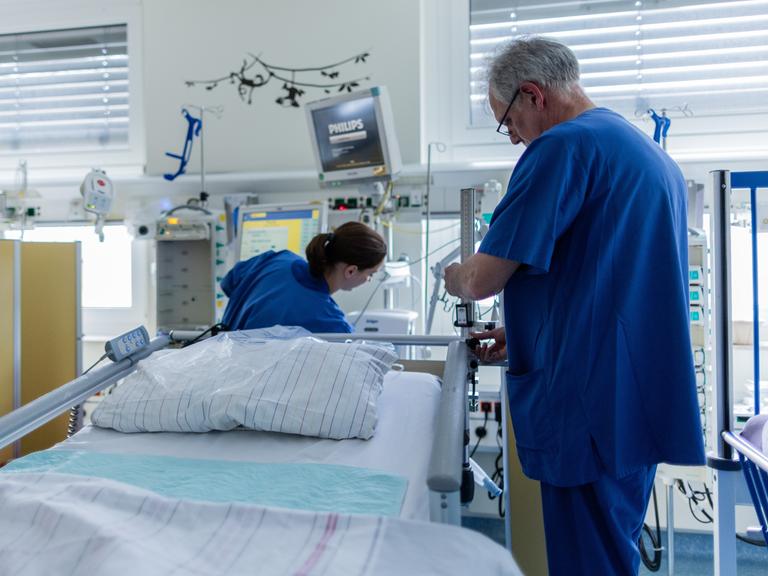 In einem Krankenhaus richten eine Pflegerin und Pfleger ein Intensivbett her.