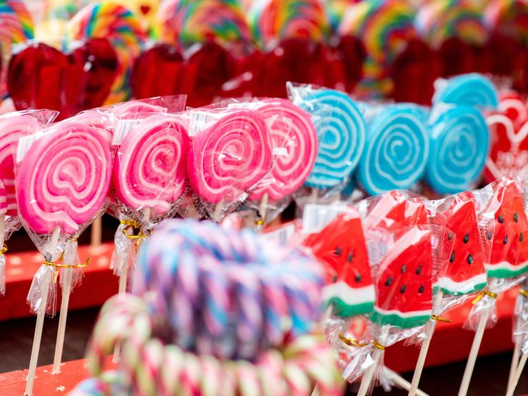 Bunte Lutscher werden während eines Volksfestes an einem Stand zum Kauf angeboten.