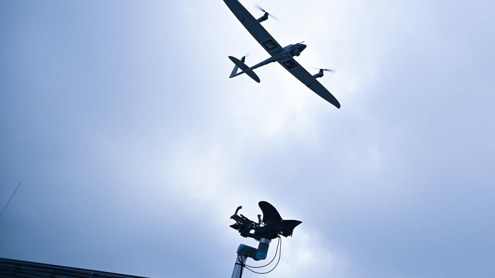 Am Himmel ist eine Drohne zu sehen. Am unteren Rand des Bildes ragt eine Sendeantenne ins Bild.
