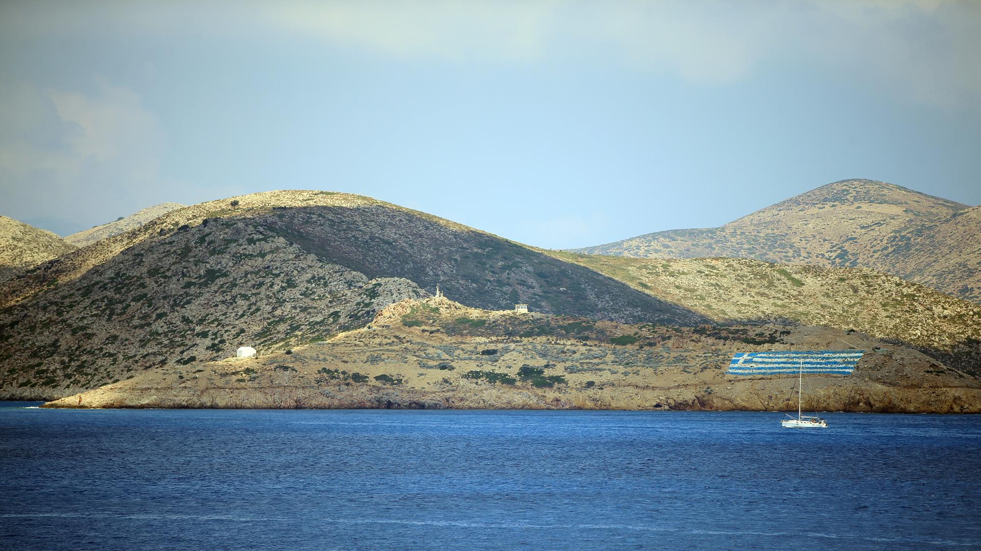 Ansicht der Ägäis-Insel Pserimos mit einer griechischen Flagge und militärischen Gebäudekomplexen.