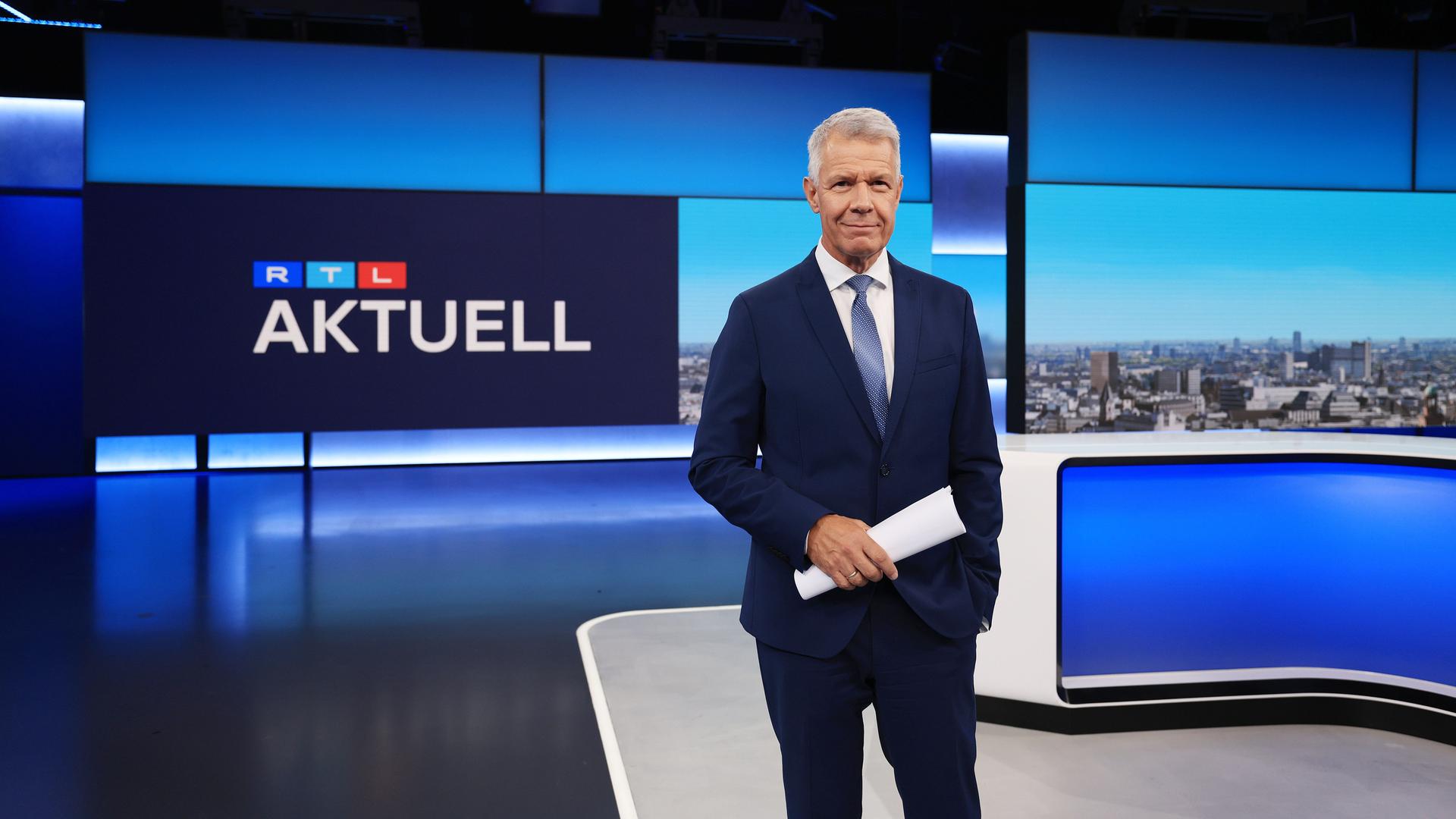 Nachrichtenmoderator Peter Kloeppel steht in einem Fernsehstudio, im Hintergrund steht "RTL Aktuell" an der Wand.