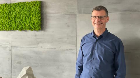 Betontechniker Dirk Dalichow in seinem Büro. Er trägt ein blaues Hemd.
