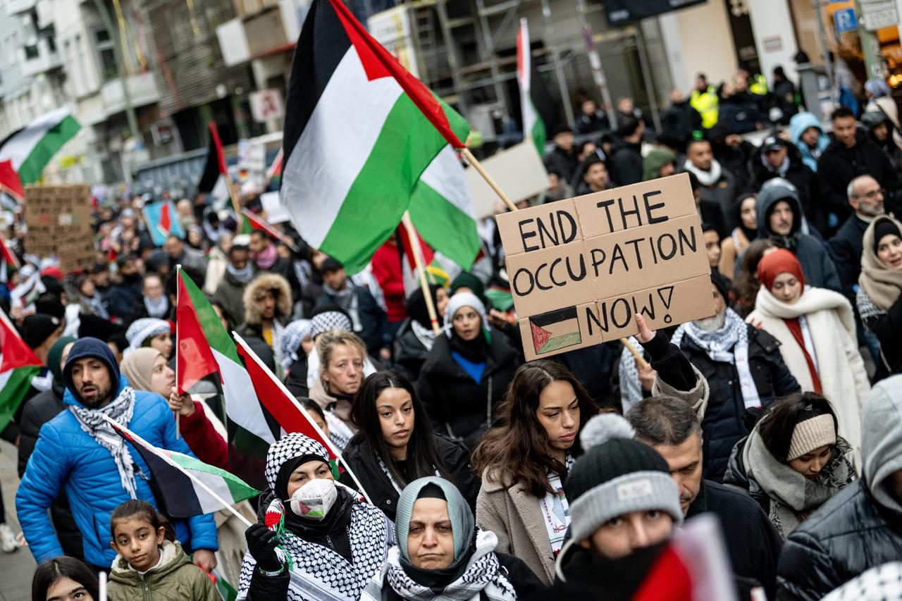 Menschen nehmen mit Schildern mit der Aufschrift "End the occupation now" an einer Demonstration für Palästina in Berlin-Mitte teil.