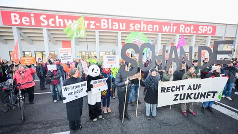Demonstranten mit Plakaten und Schildern, die das Wort "Schande" bilden, stehen vor Beginn des 37. Bundesparteitag der CDU im CityCube Berlin vor dem Veranstaltungsgelände. 