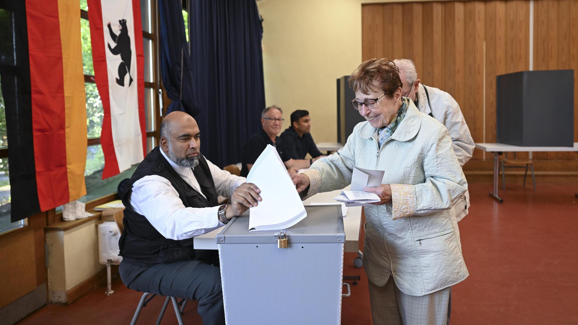 Eine ältere Dame steckt ihren Stimmzettel bei der Wahl in Berlin in eine Wahlurne.