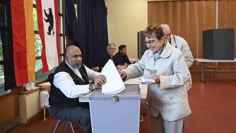 Eine ältere Dame steckt ihren Stimmzettel bei der Wahl in Berlin in eine Wahlurne.