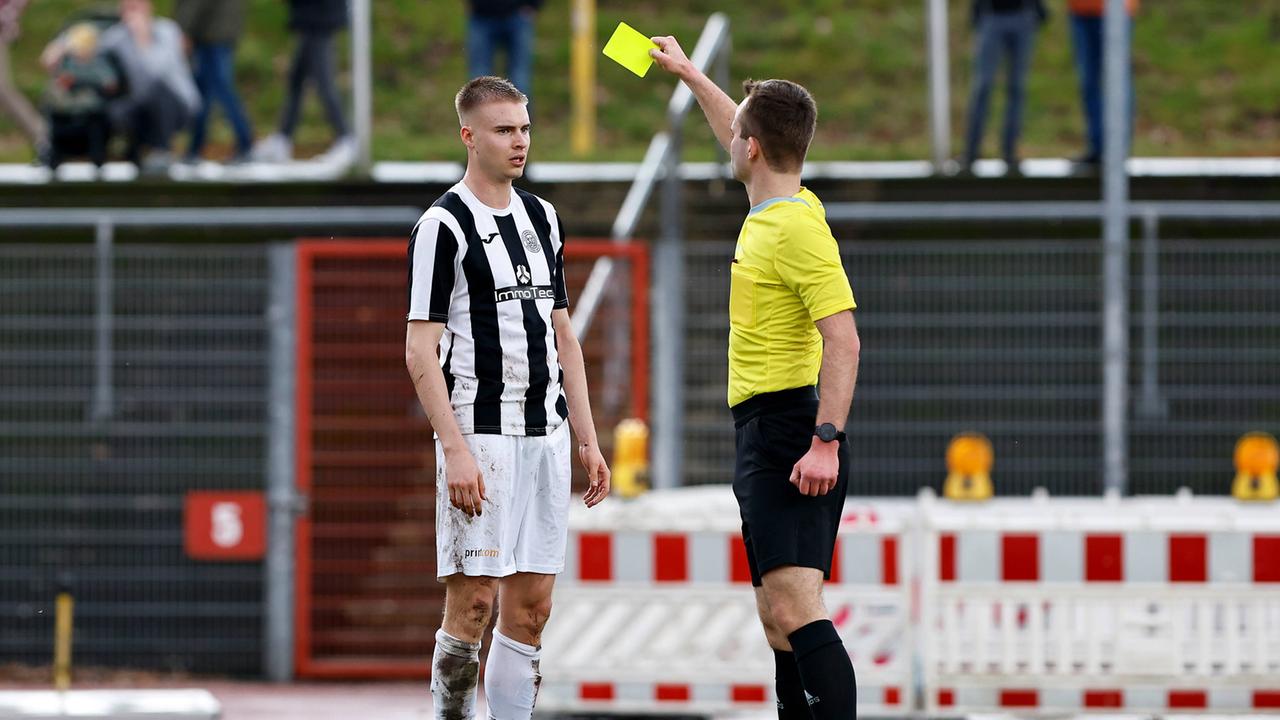 Ein Schiedsrichter zeigt einem Fußballspieler die Gelbe Karte.