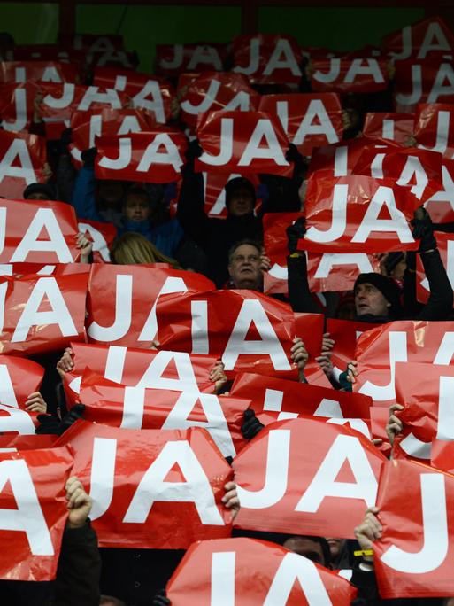 Fans des SC Freiburg halten auf der Tribüne im alten Stadion rote Schilder mit der Aufschrift "JA" in weißen Buchstaben hoch. Es sind rund 50 Schilder zu sehen und kaum Gesichter, da diese hinter dem Schilderwald nicht zu sehen sind. 