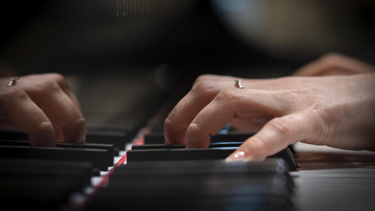Hand einer jungen Pianistin die auf der Klaviatur eines Flügels spielt.