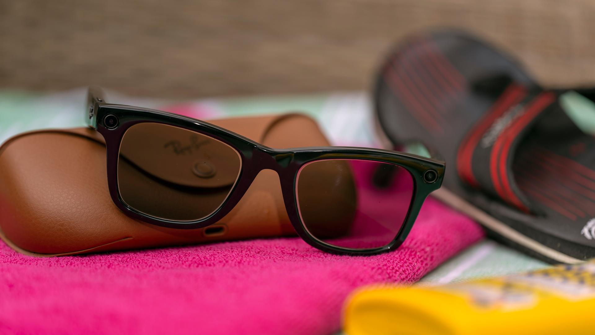 Eine Smart Glasses liegt auf einem Strandhandtuch zwischen Sonnencreme und Badelatschen. Eine Smart Glasses liegt auf einem Strandhandtuch zwischen Sonnencreme und Badelatschen.