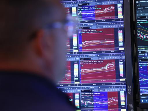 Ein Trader an der New Yorker Börse beobachtet einen Bildschirm mit mehreren Aktienindexen.