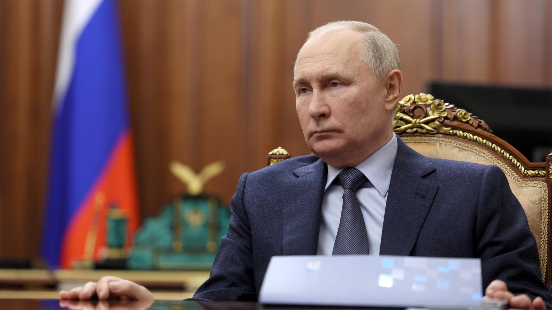 Der russische Präsident Putin sitzt an einem Holztisch.
