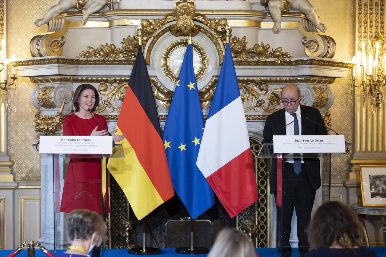 Bundesaußenministerin Annalena Baerbock (l.) und der französische Außenminister Jean-Yves Le Drian geben eine Pressekonferenz. Beide stehen an einem Redepult. Baerbock macht eine Geste zu Le Drian. Der Saal ist mit goldenen Ornamenten geschmückt.
