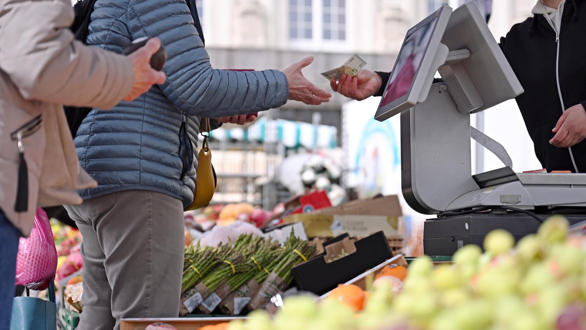 Eine Frau erhält Rückgeld an einem Marktstand auf dem Leipziger Markt. Steigende Preise und die Entwicklung der Inflation belasten viele Verbraucher im Alltag. 