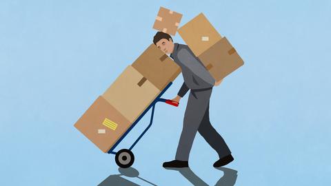 Ein Paketbote der eingequetscht zwischen Kistenstapeln Pakete ausliefert.