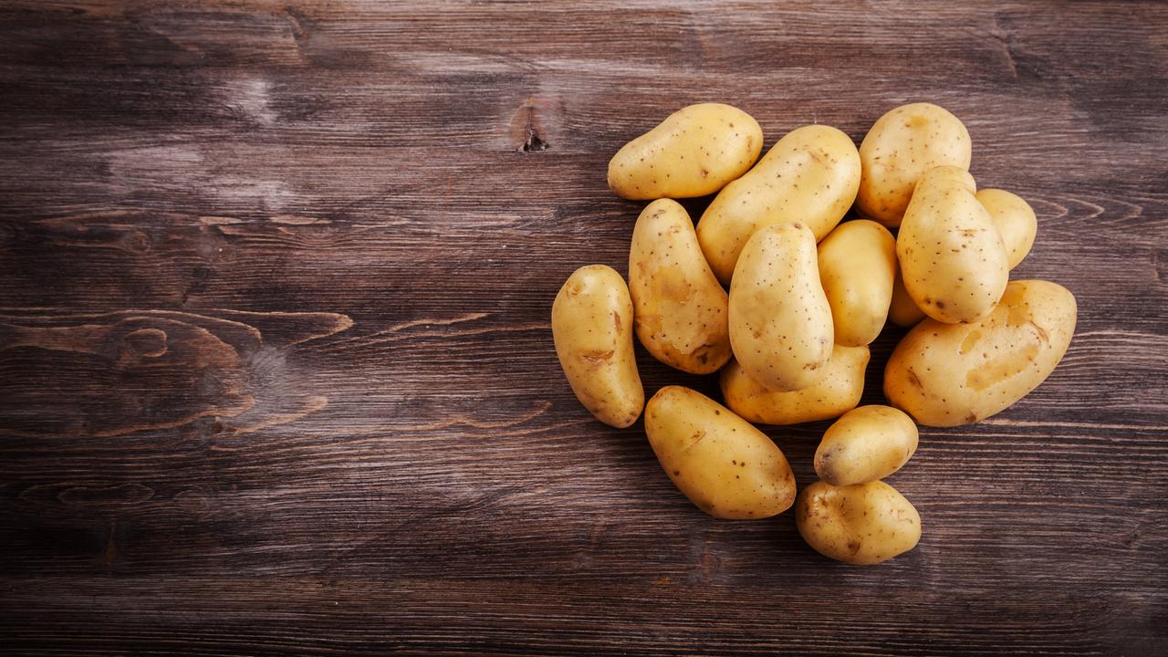 Das Bild zeigt einen Blick von oben auf ein Holzfläche, auf der Kartoffeln zu einer Gruppe zurechtgelegt sind