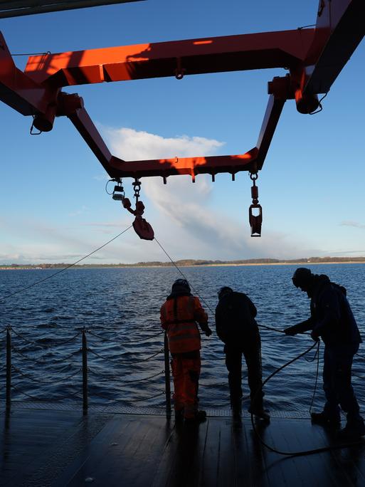 Besatzungsmitglieder ziehen in der Ostsee ein Kabel an Deck eines Forschungsschiffs. Mehr als fünf Jahre nach dem mysteriösen Verschwinden eines auf dem Grund fest verankerten Unterwasserobservatoriums gibt es neue Datensammler am Meeresgrund.