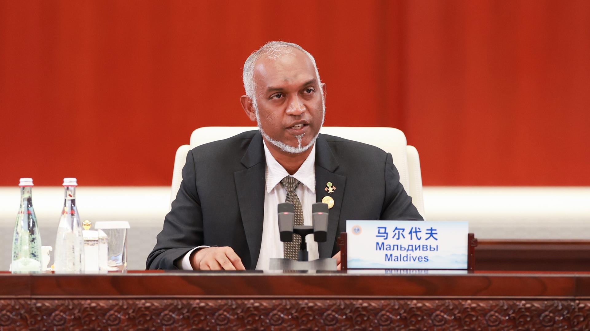 Der Präsident der Malediven, Mohamed Muizzu sitzt in einer Veranstaltung hinter Mikrofonen.