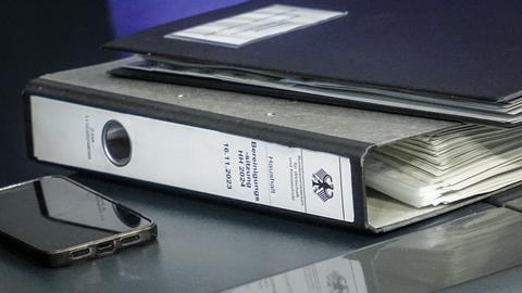 Ein Aktenordner mit der Aufschrift "Haushalt - Bereinigungssitzung HH 2025 16.11.2023" liegt auf einem Tisch im Bundestag.